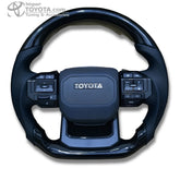 Timón cabrilla tipo GR 2026 para Toyota, negro brillante con cuero perforado - vista frontal - Importoyota Colombia
