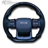 Timón cabrilla tipo GR 2026 para Toyota, negro brillante con cuero perforado - vista frontal - Importoyota Colombia